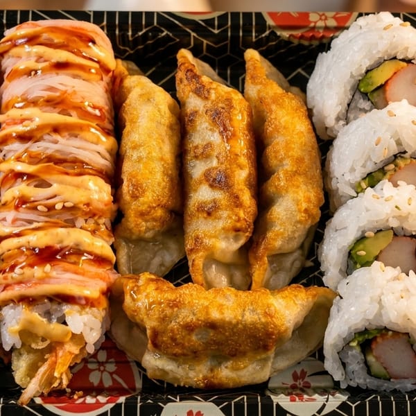 A takeout tray with two rows of sushi rolls, a row of gyoza, and another row of sushi.